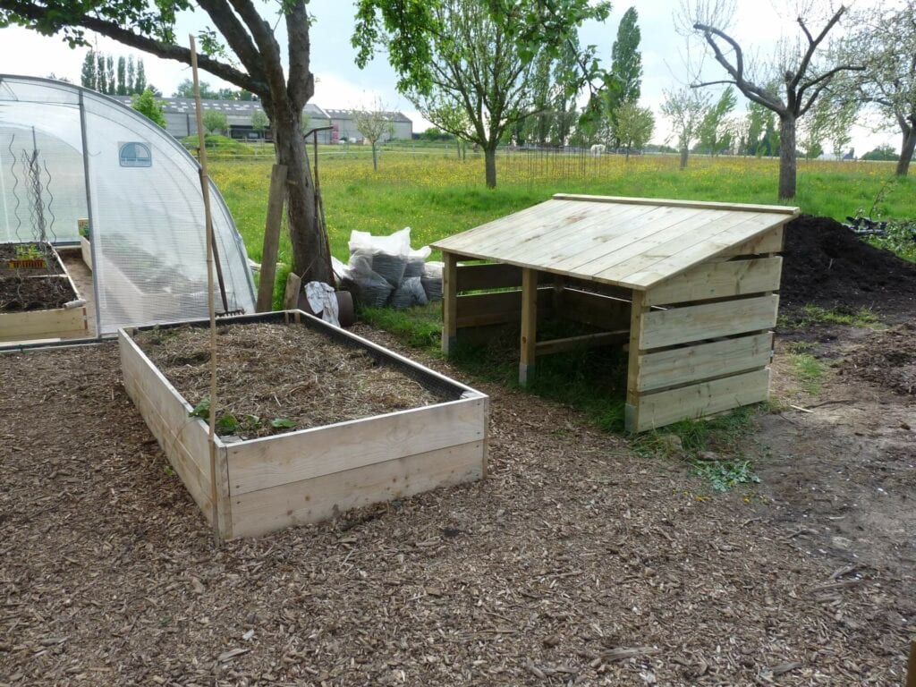 Composteur en bois installé dans le potager surélevé